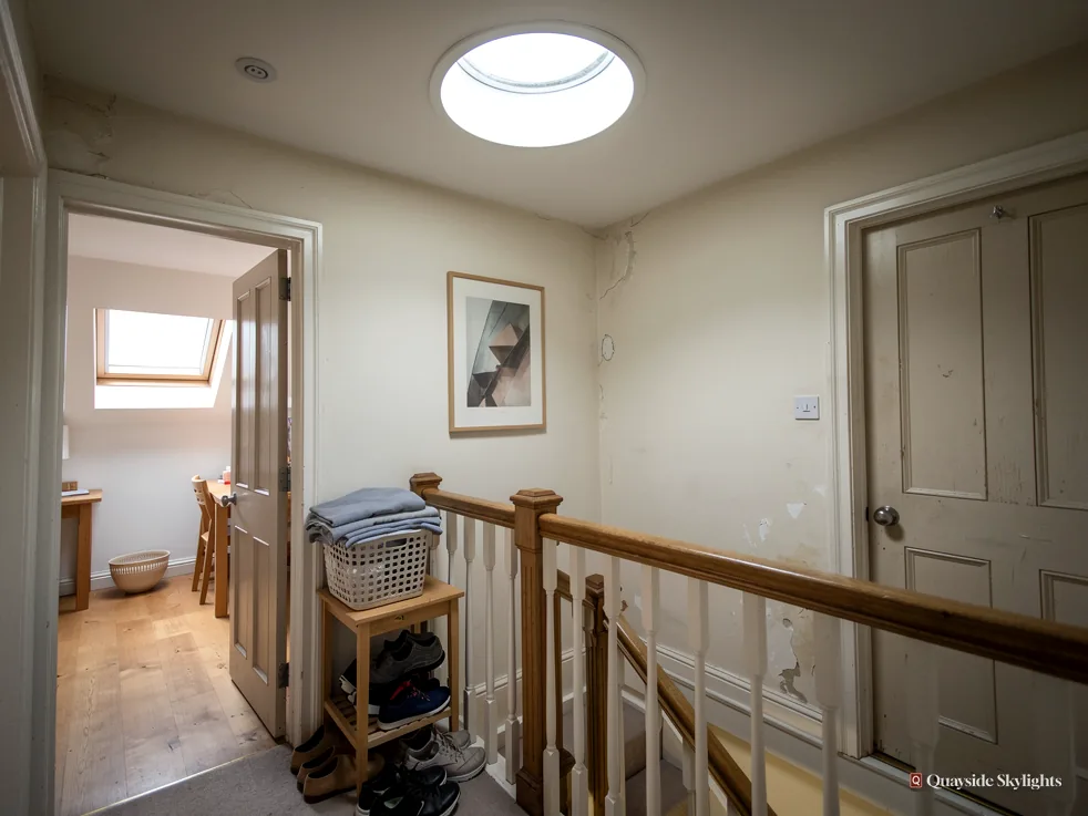 Hallway ceiling with a round sun tunnel diffuser, a landing banister and a doorway to a loft room