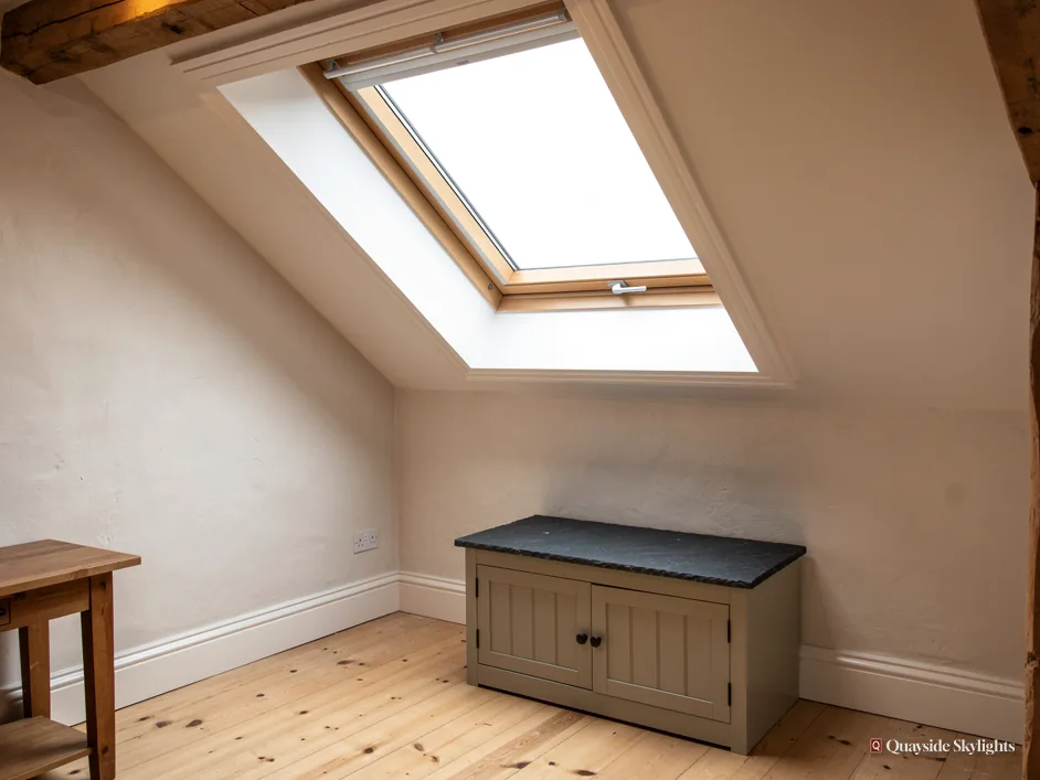 Loft room with a pine roof window above a painted storage bench and a small side table