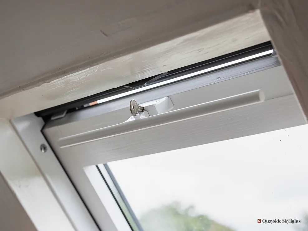 Close view of an open roof window sash, its frame and handle seen from inside