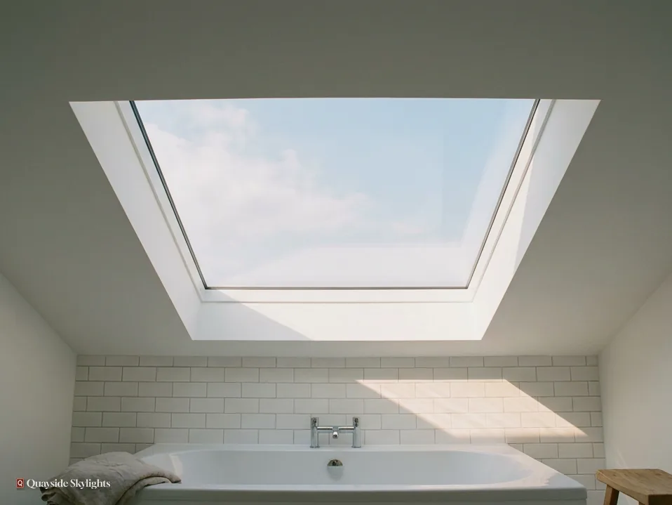 Bathroom with a white bath and metro tiles under a large frameless flat rooflight