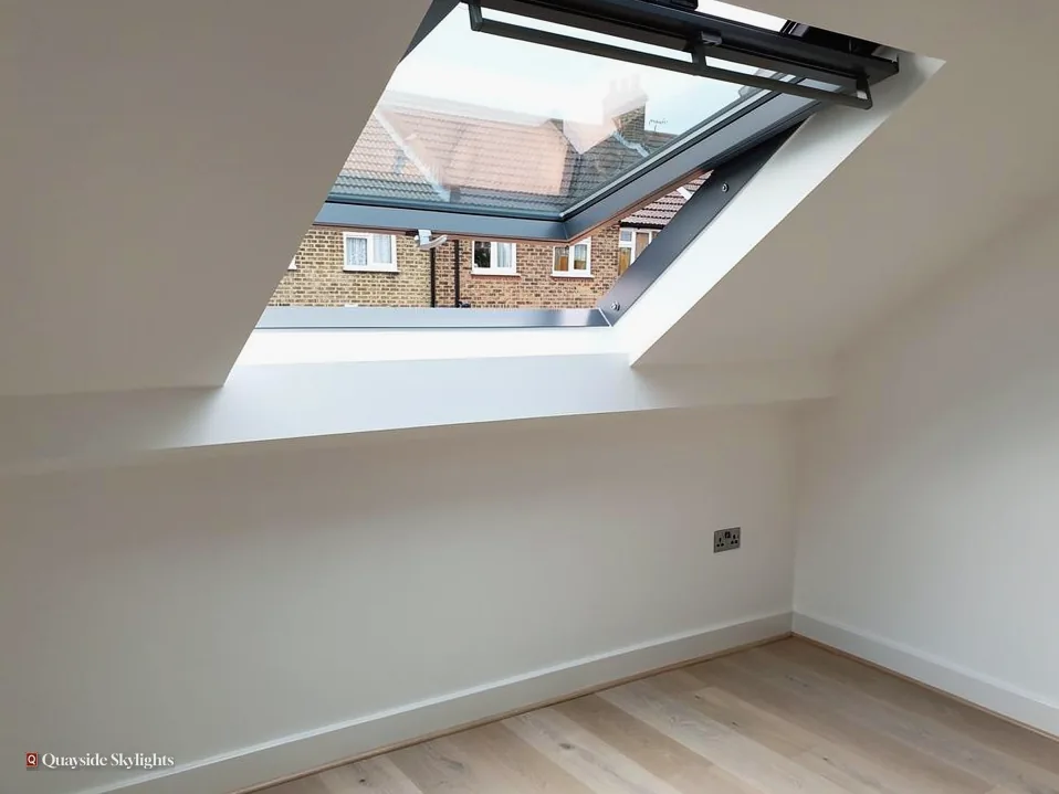 Bright white loft room with a roof window opened onto a view of neighbouring roofs