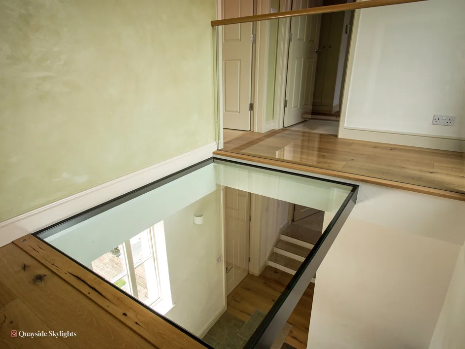 Walk-on glass panel set into a timber floor, looking down into the room below