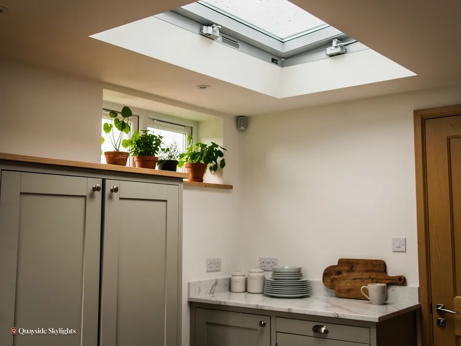 Kitchen with an opening flat rooflight and visible motor arm above shaker units and a window