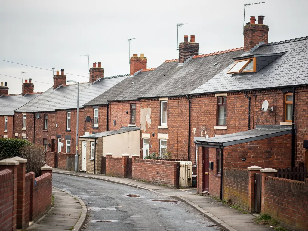 Curving street of red brick terraces with chimneys and a dormer on a grey day