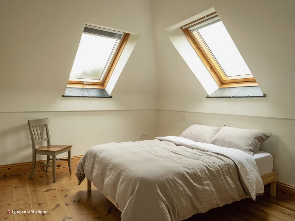 Bare loft bedroom with two timber roof windows, a wooden chair and a bed