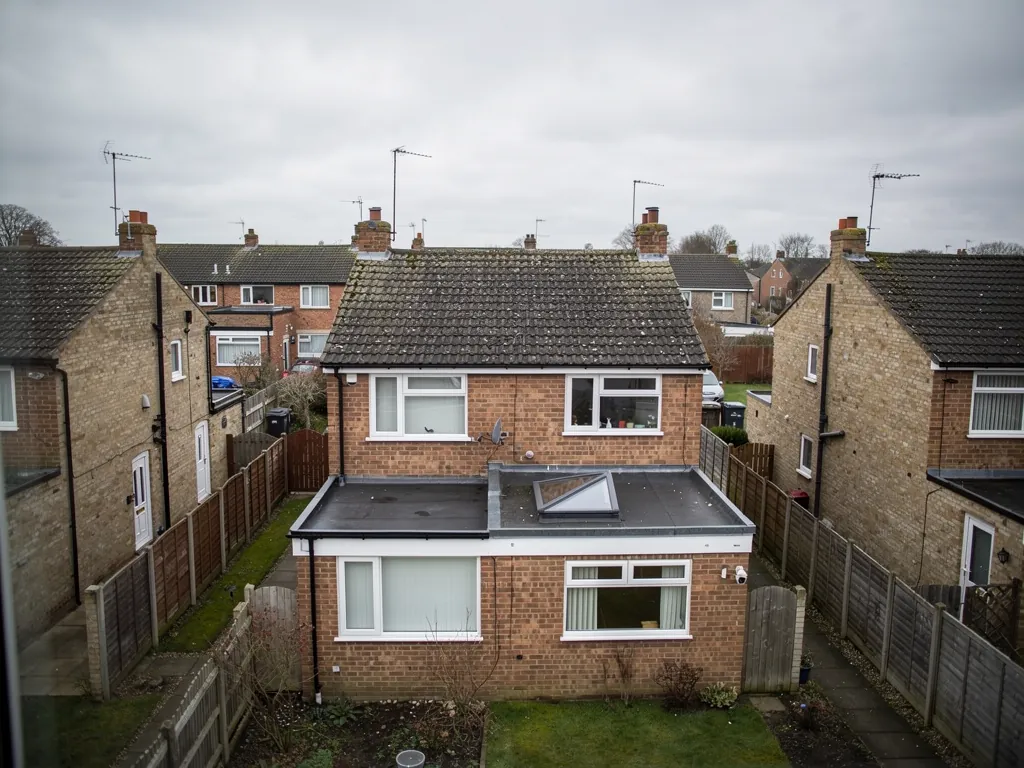 Rear of a brick house with a single-storey extension and rooflights, neighbouring homes around