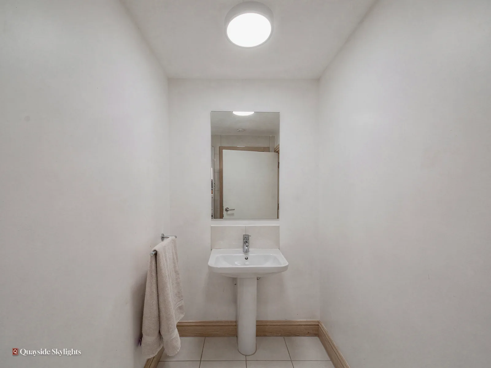 Small windowless bathroom with a pedestal basin, mirror and round ceiling light