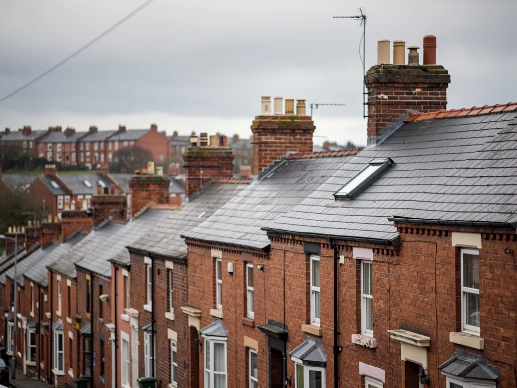 Rooftops of brick terraced houses with slate roofs, chimneys and one roof window