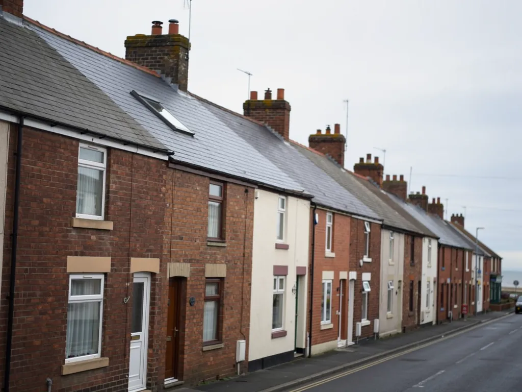 Long street of brick and painted terraced houses with roof windows
