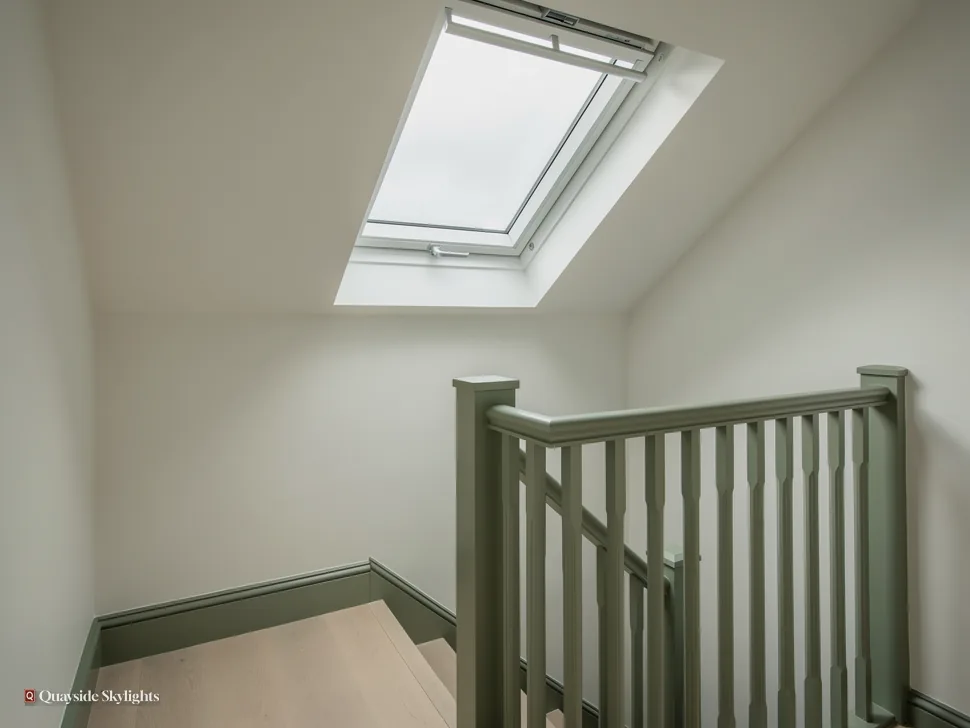 Stairwell with a green painted rail climbing towards a roof window