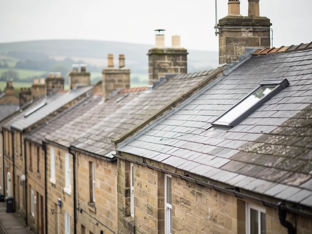 Sandstone terraces with slate roofs and a roof window above green hills