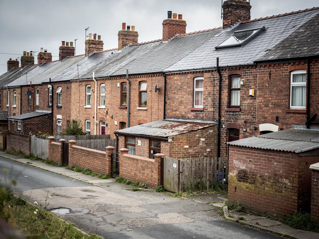 Back of red brick terraces with outhouses and yards along a lane