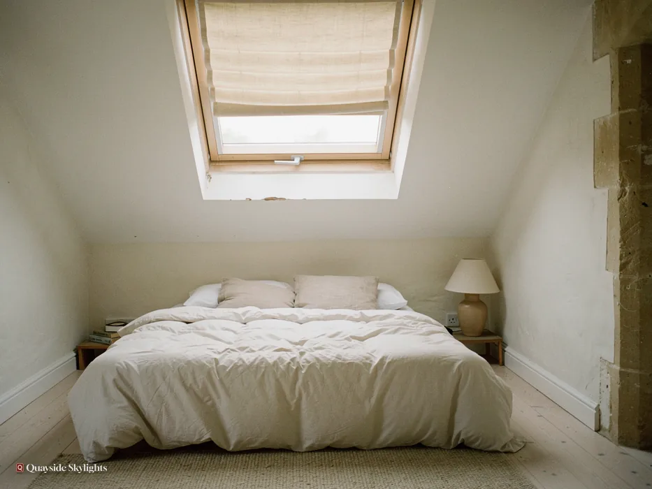 Small bedroom with a cream blind on a roof window above a double bed