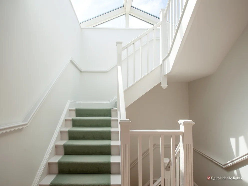 White stairwell with a green stair runner and glazing overhead