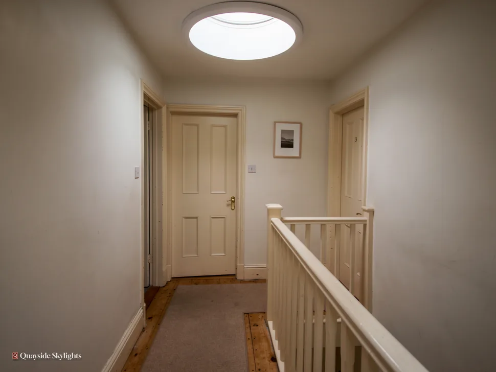 Landing with a round sun tunnel diffuser, white panelled doors and banister
