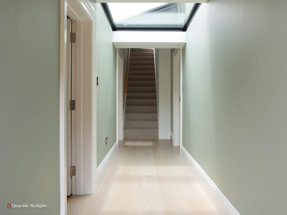 Long narrow hallway leading to stairs under a flat rooflight