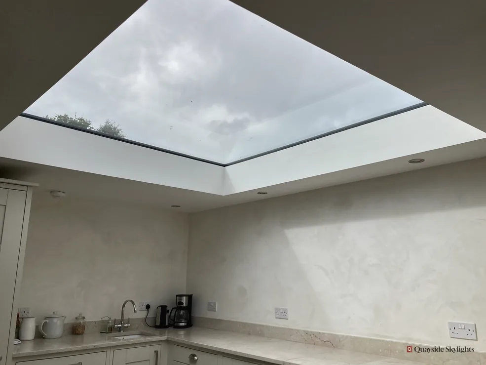 Kitchen corner with a sink and coffee machine under a large flat rooflight
