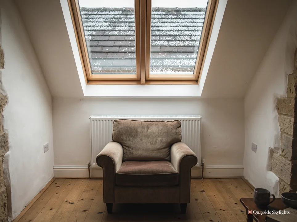 Room with twin roof windows above an armchair and white radiator