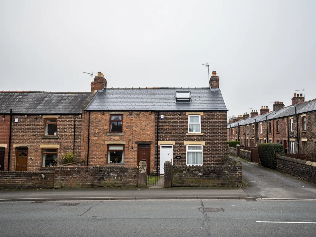 Brick terraced houses with chimneys facing a quiet road