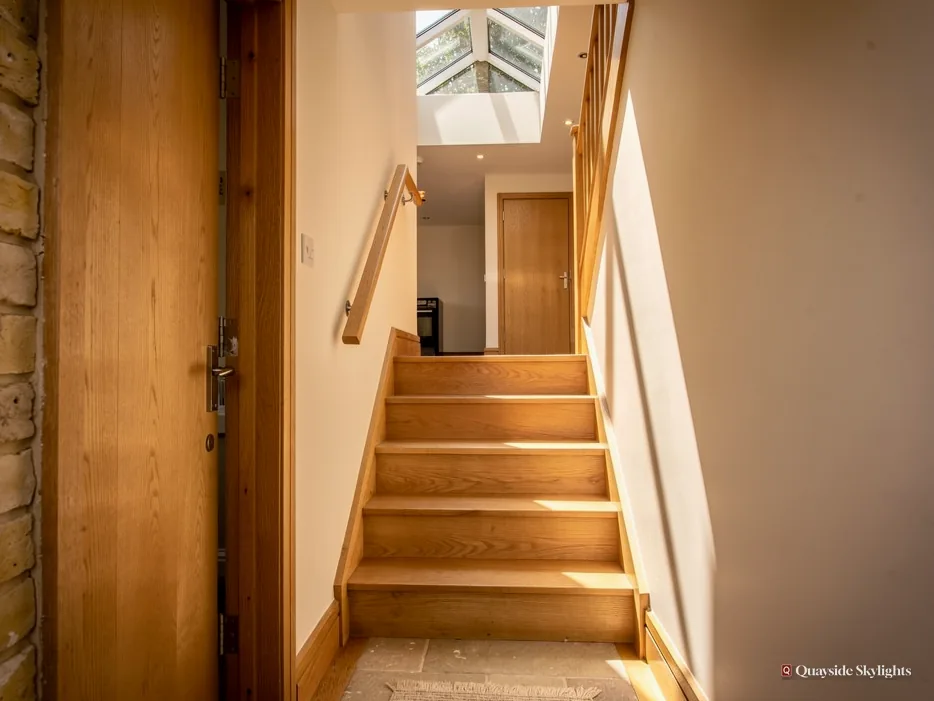 Narrow oak staircase rising to a glazed rooflight