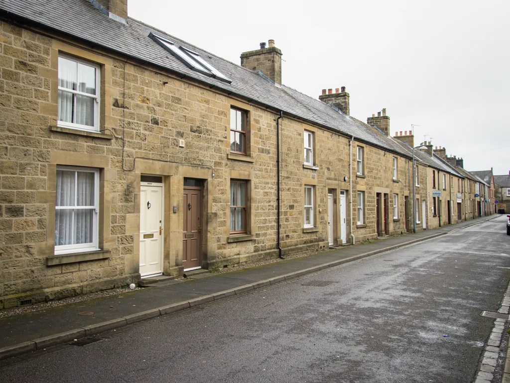 Sandstone terraced houses with slate roofs and roof windows along a street