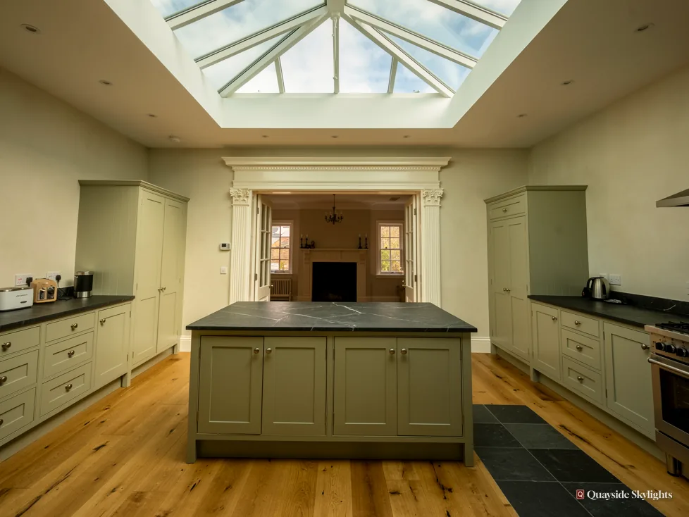Kitchen with a sage green island beneath a roof lantern