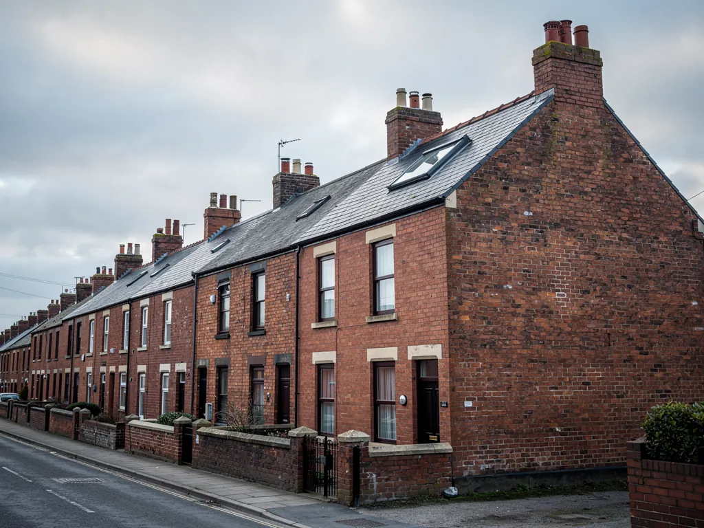 Gable end of a brick terraced row with roof windows on the slate roof
