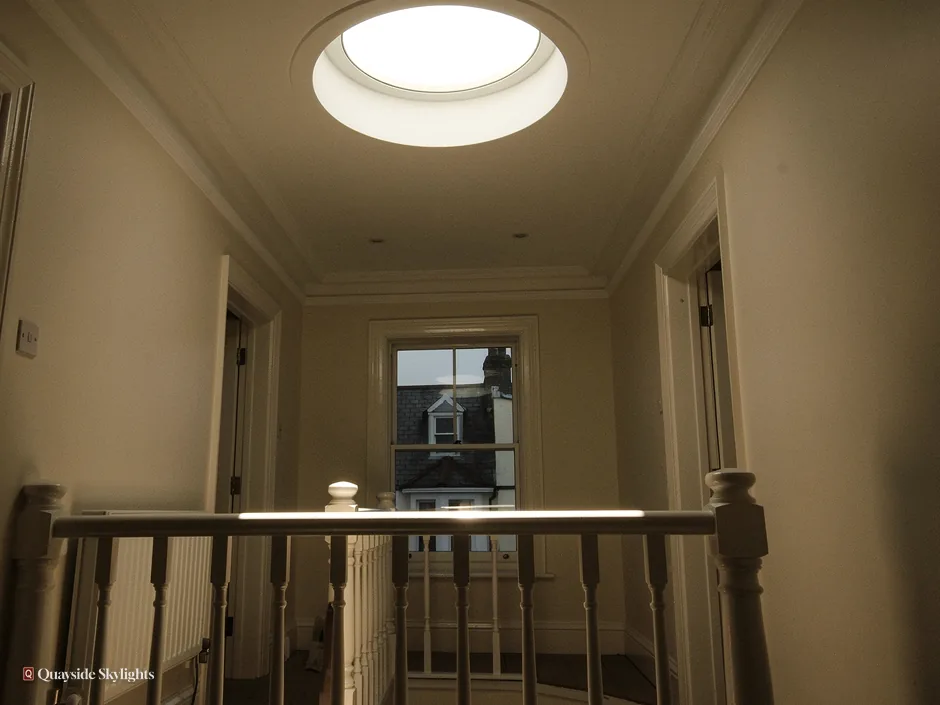 Dim landing with a round sun tunnel diffuser over the stair rail