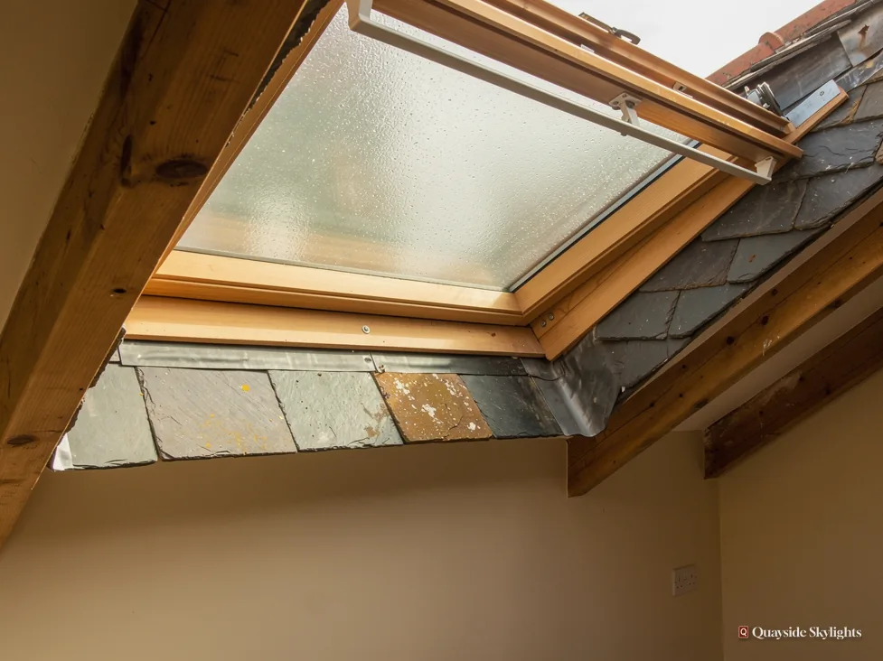 Misted pine roof window seen from below with slates visible through the glass