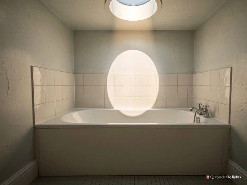 Bath beneath a sun tunnel casting an oval of light on tiled walls