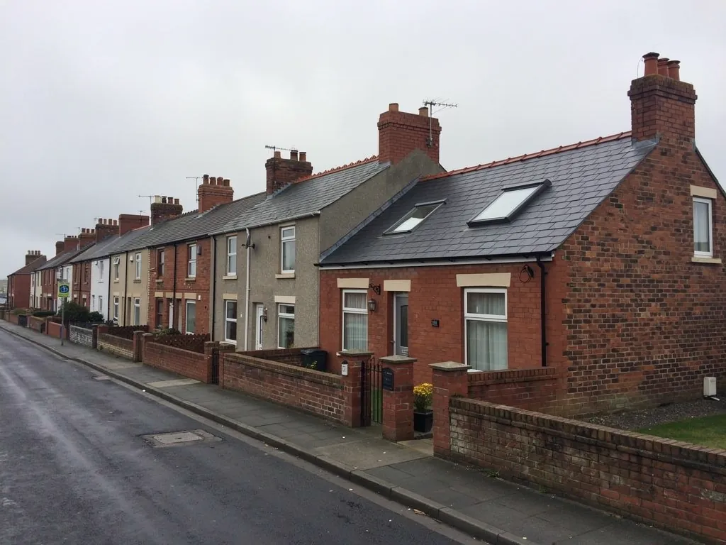 Brick terraced row with roof windows on a grey residential street