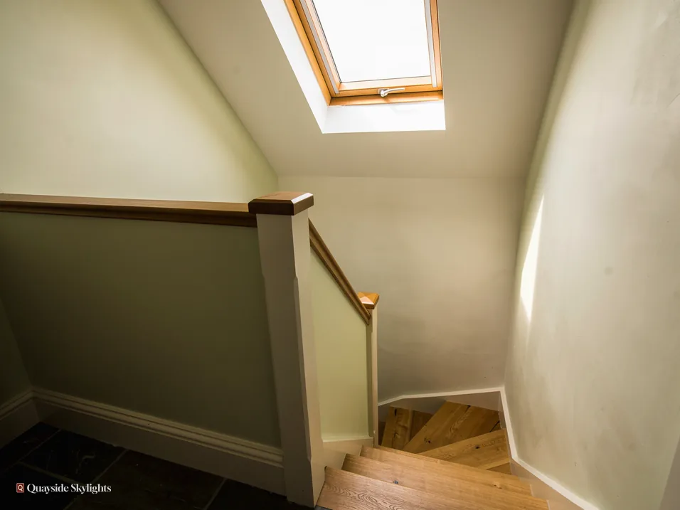Stairwell with grey-green walls rising to a pine roof window