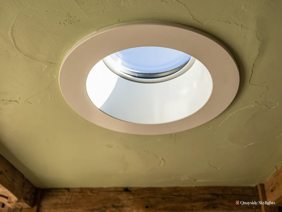 Close view of a round sun tunnel diffuser set in a plaster ceiling