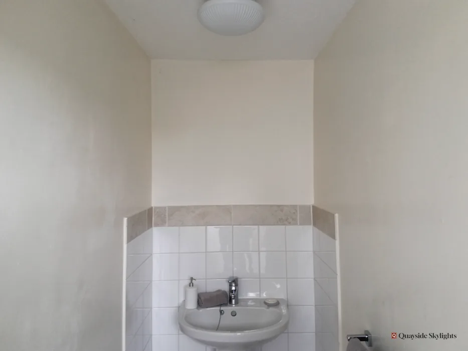 Small cloakroom with a basin, white tiles and a ceiling light