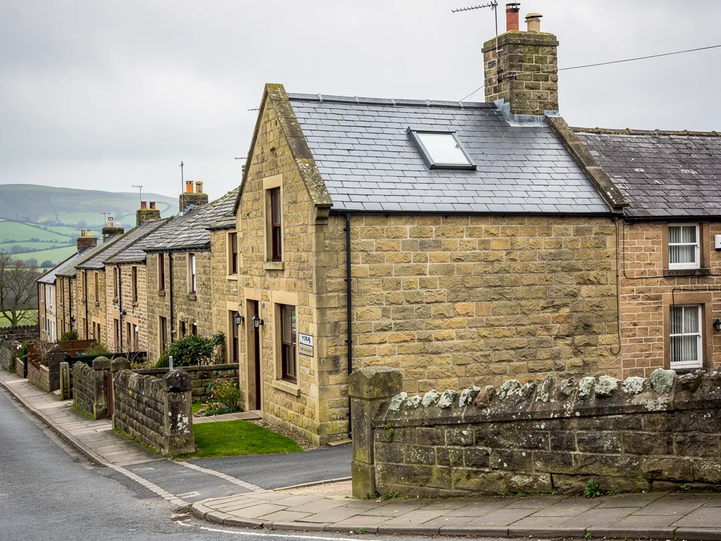 Stone terraced row on a hillside lane with green hills beyond