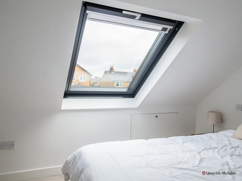 Bedroom with a grey roof window looking out over houses