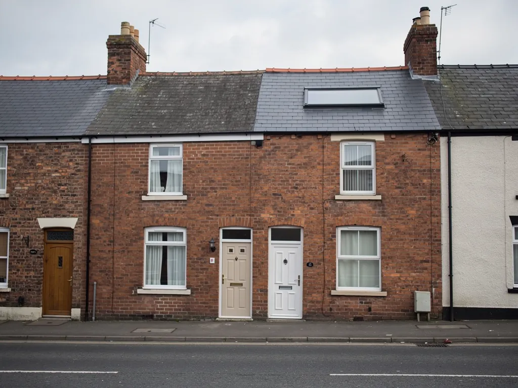 Brick terraced fronts with a roof window beside a painted neighbour