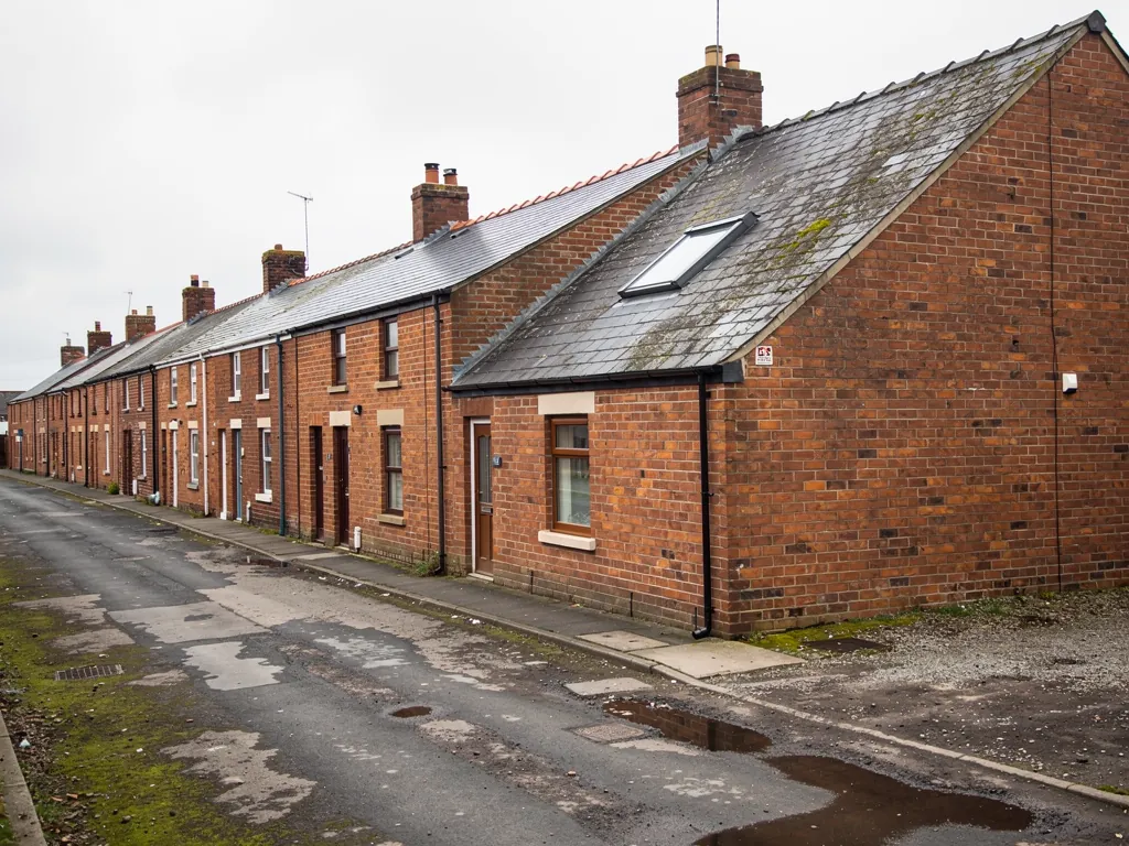 Brick terraced row along a broken lane with puddles