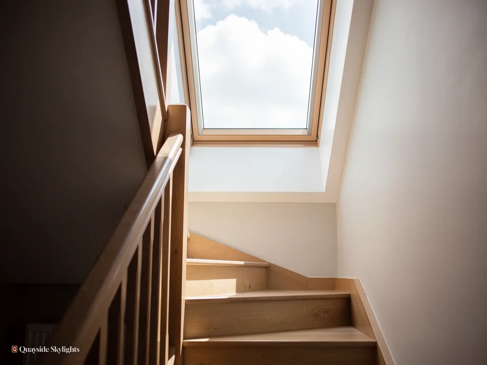 Winding timber staircase lit from a roof window above