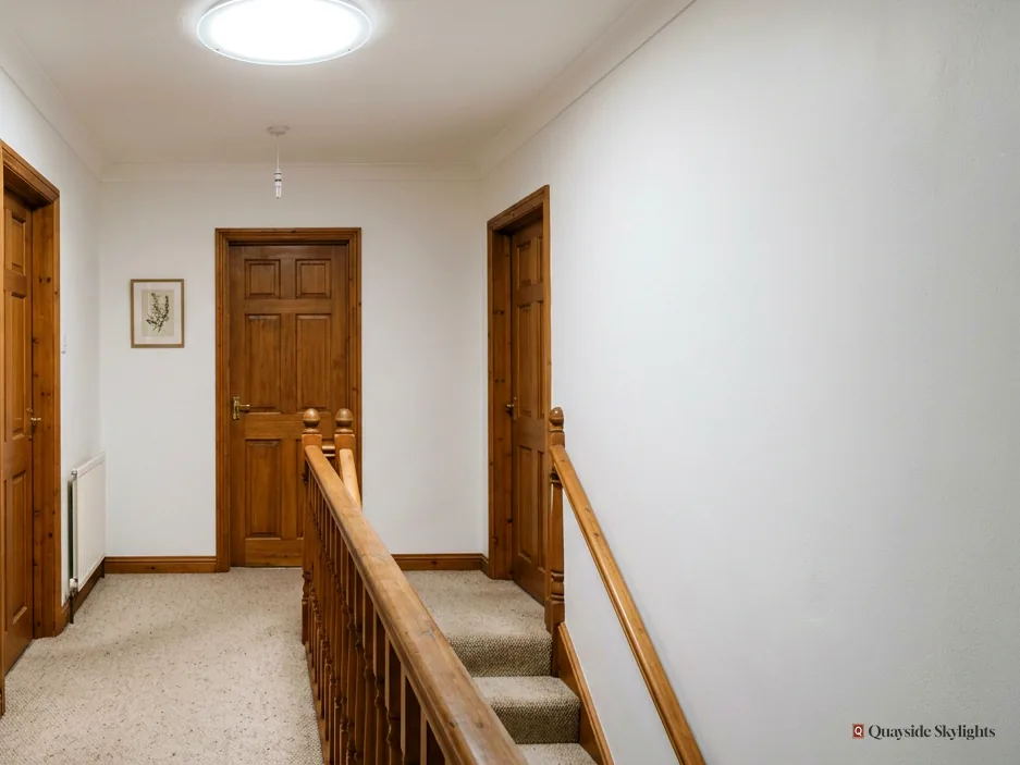 Landing with a sun tunnel diffuser, wooden doors and a carpeted stair