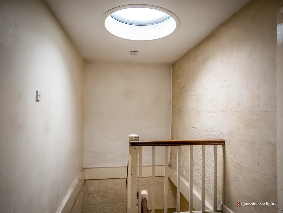 Bare landing with a white balustrade beneath a sun tunnel diffuser