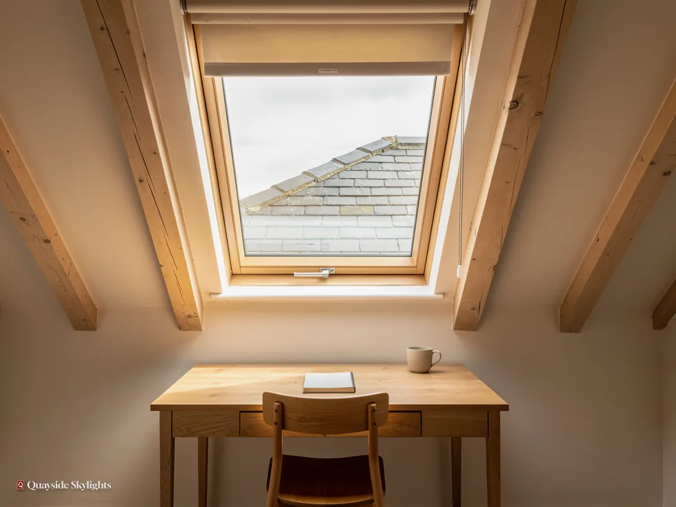 Wooden desk and chair below a pine roof window between rafters