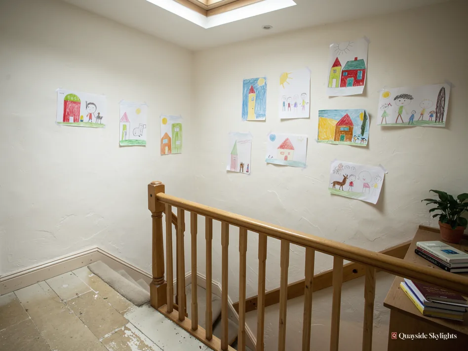 Landing with children's drawings pinned along the wall above a wooden stair rail