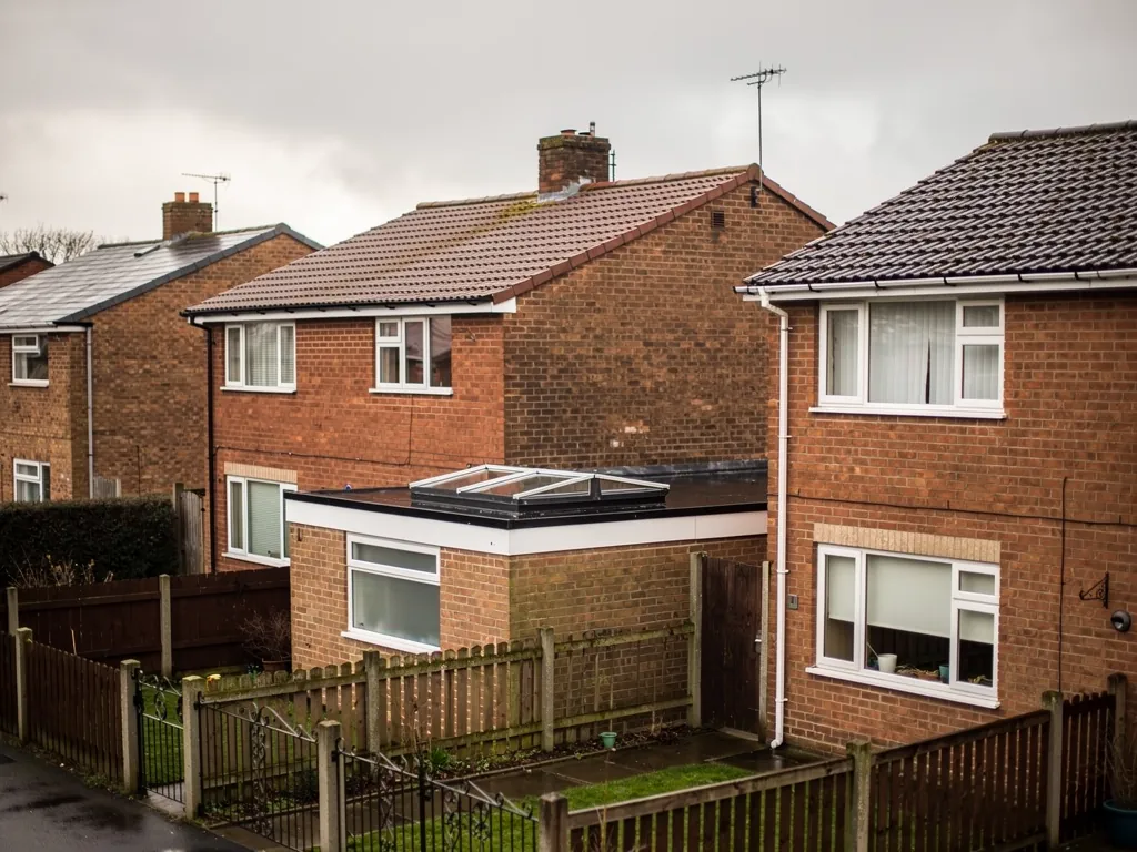 Brick semis with a flat-roofed rear extension and rooflight above a garden