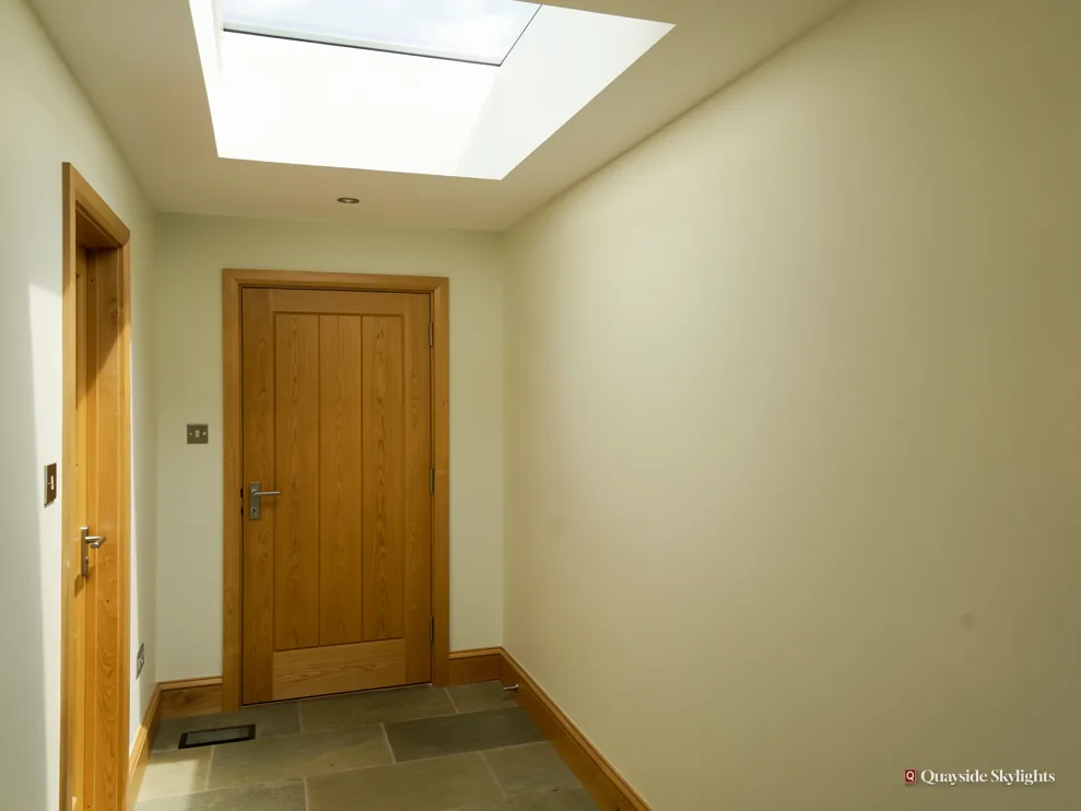 Hallway with an oak door and stone floor beneath a flat rooflight