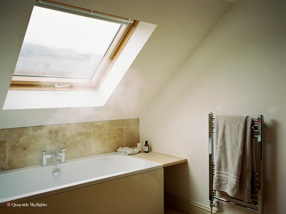 Bath and heated towel rail under a roof window in a steamy bathroom