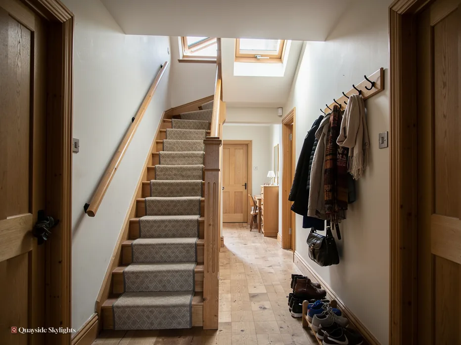 Hallway with a carpeted staircase, coats on hooks and a rooflight above
