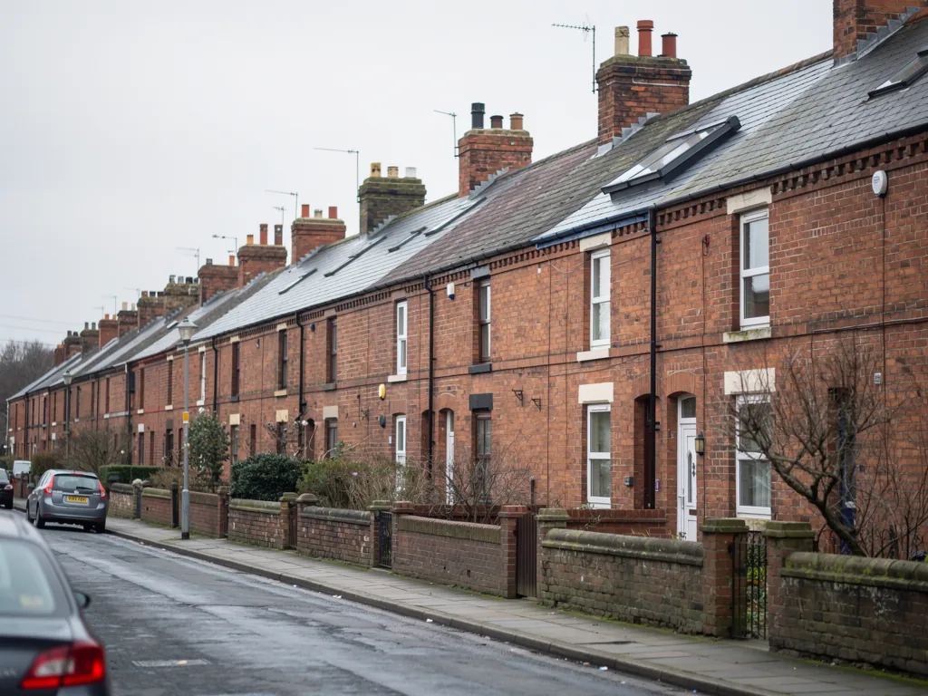 Long brick terraced street with cars parked along the kerb