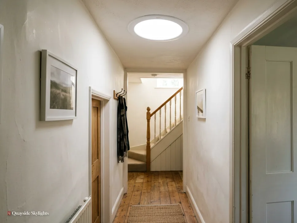 Hallway with a framed print and stairs, lit by a round sun tunnel