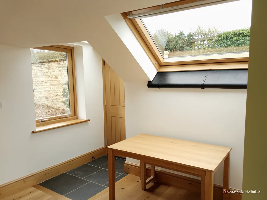 Small room with a pine table beside a roof window and a side window